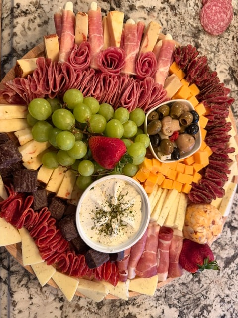 Charcuterie board with cured meats, cheeses, olives, and grapes
