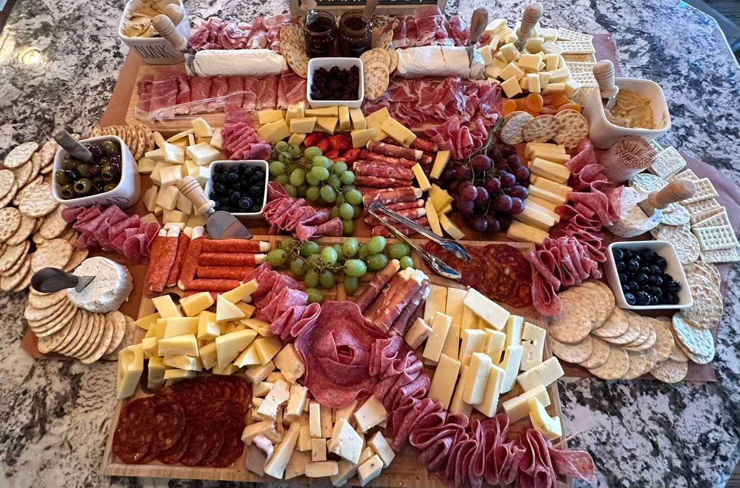 Abundant charcuterie and cheese board with meats, fruit, crackers, and dips