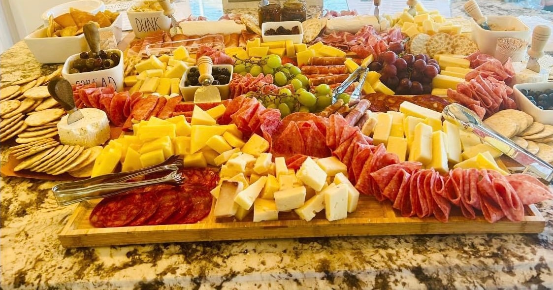 Large charcuterie grazing board with cheeses, cured meats, fruit, and crackers