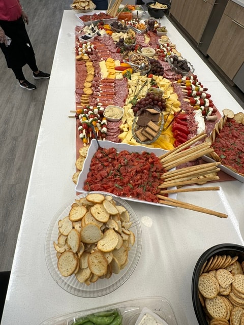 Long charcuterie and appetizer table with meats, cheeses, vegetables, and bread