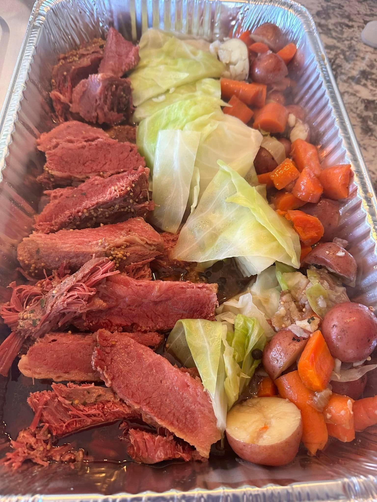 Corned beef with cabbage, carrots, and potatoes in a catering tray